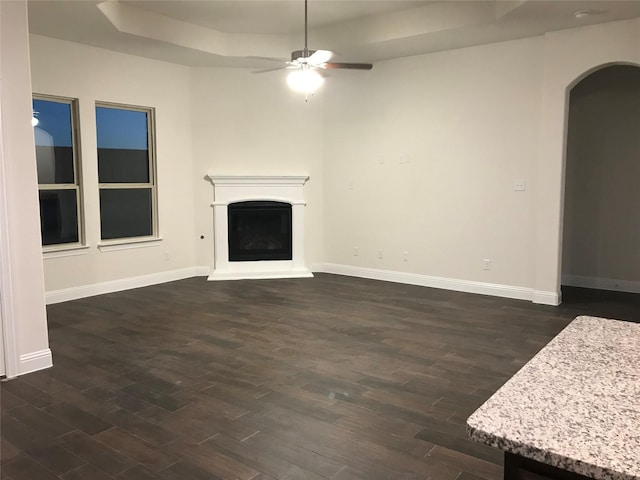4111 Beamer Dr, Forney, TX 75126 - unfurnished living room featuring baseboards, a fireplace with raised hearth, arched walkways, ceiling fan, and dark wood finished floors