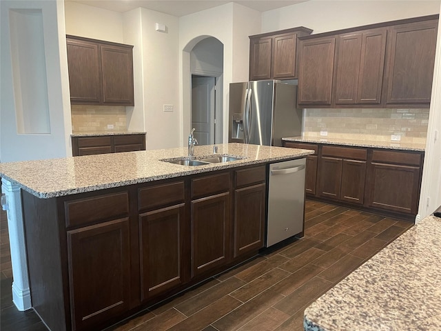 4111 Beamer Dr, Forney, TX 75126 - kitchen with arched walkways, a sink, appliances with stainless steel finishes, dark brown cabinets, and wood finish floors