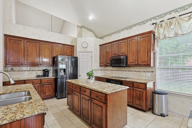 kitchen featuring light stone counters, light tile patterned flooring, sink, appliances with stainless steel finishes, and a center island