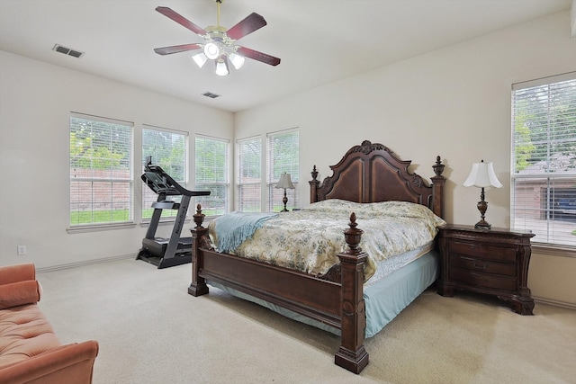 bedroom with ceiling fan, light carpet, and multiple windows