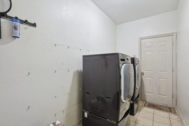 clothes washing area with washer and clothes dryer and light tile patterned floors