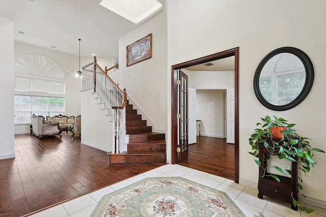 foyer featuring light hardwood / wood-style flooring, a towering ceiling, and a skylight