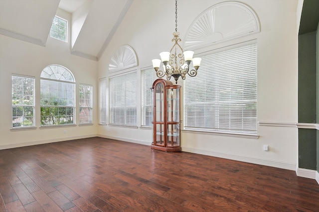 empty room featuring crown molding, a chandelier, dark wood-type flooring, and high vaulted ceiling