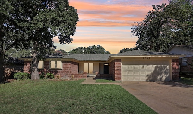 ranch-style home featuring a lawn and a garage