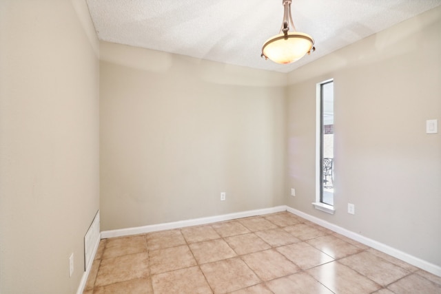 spare room with a textured ceiling and light tile patterned floors