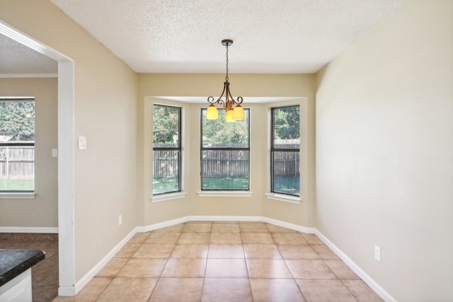 unfurnished dining area featuring a textured ceiling, a chandelier, light tile patterned floors, and a wealth of natural light