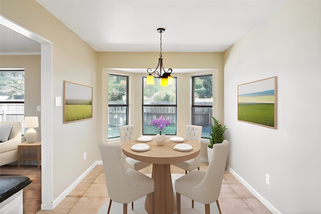 tiled dining room featuring a healthy amount of sunlight, crown molding, and an inviting chandelier