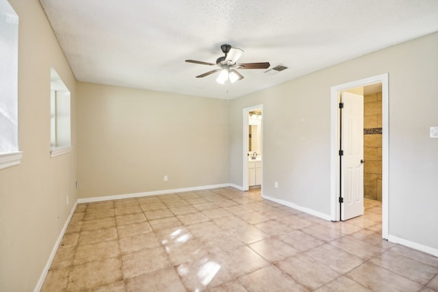 unfurnished room with ceiling fan, light tile patterned flooring, and a textured ceiling