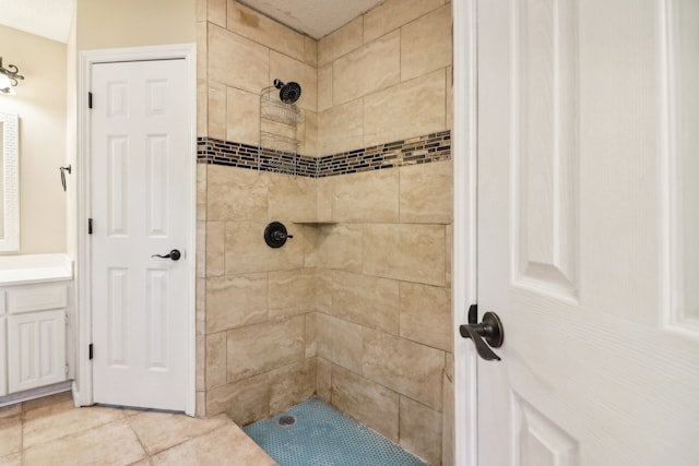 bathroom with a tile shower, tile patterned floors, and vanity