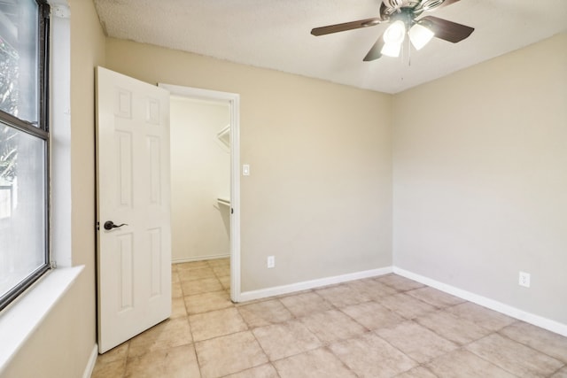 spare room featuring ceiling fan, light tile patterned floors, and a textured ceiling