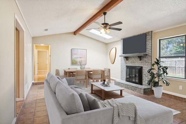 living room featuring ceiling fan, a brick fireplace, lofted ceiling with beams, and light tile patterned floors