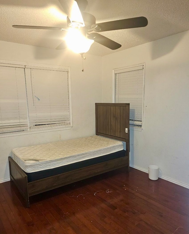 unfurnished bedroom featuring a textured ceiling, dark hardwood / wood-style floors, and ceiling fan