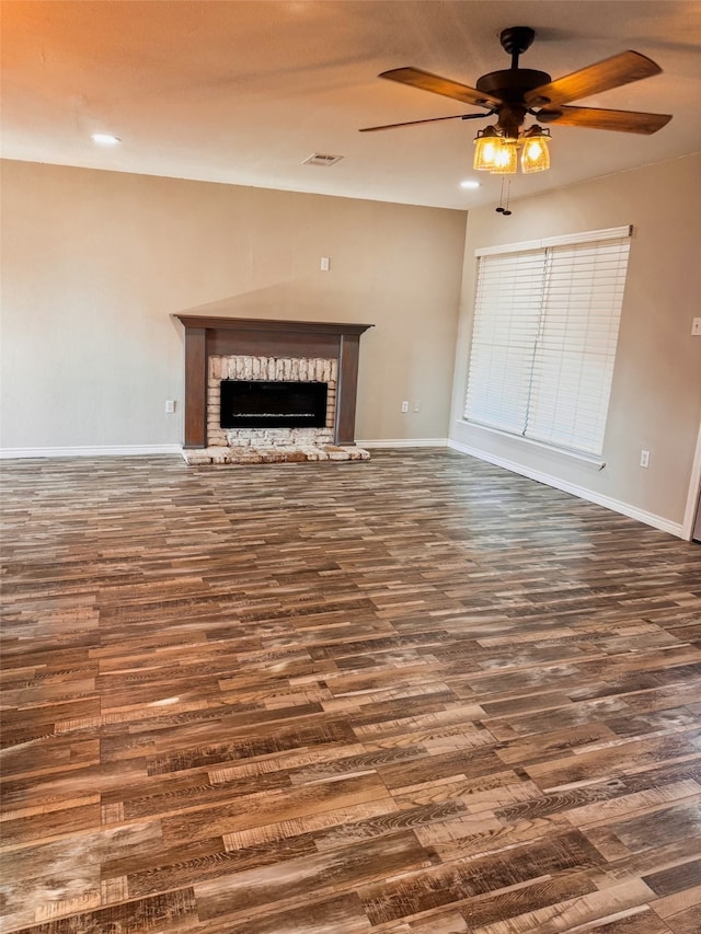 unfurnished living room featuring ceiling fan, a fireplace, and dark hardwood / wood-style floors