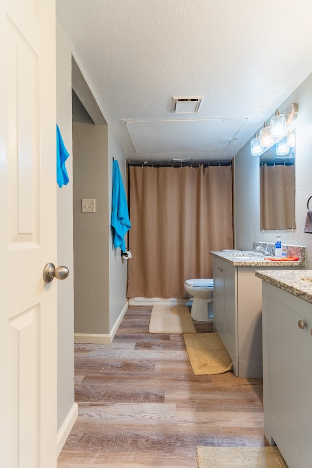 bathroom with vanity, toilet, a textured ceiling, and hardwood / wood-style flooring