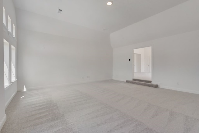 empty room featuring baseboards, visible vents, light colored carpet, vaulted ceiling, and recessed lighting