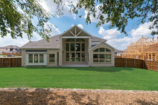 rear view of house featuring a fenced backyard, a lawn, and brick siding