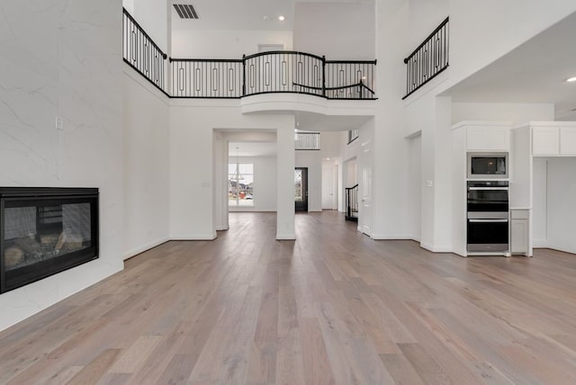 unfurnished living room featuring light wood finished floors, baseboards, a fireplace, and visible vents