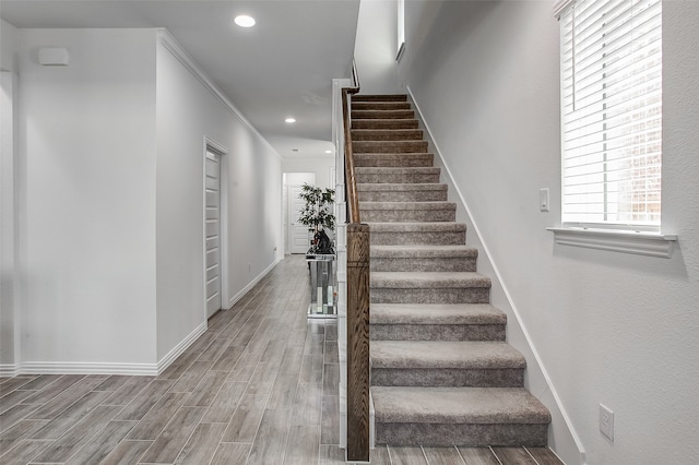 staircase featuring hardwood / wood-style flooring and crown molding