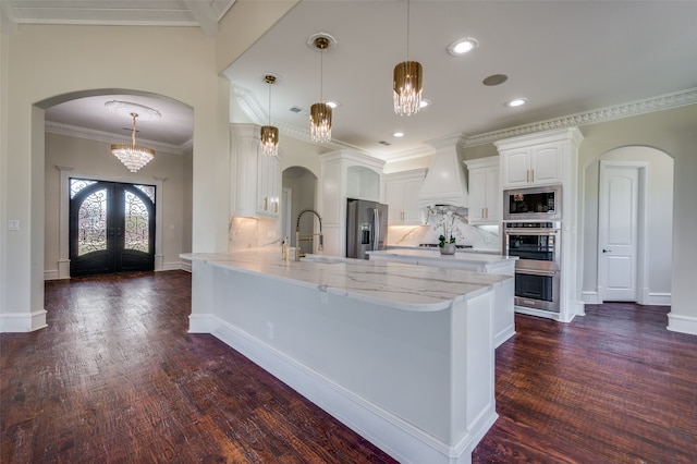 kitchen with appliances with stainless steel finishes, custom range hood, dark wood-type flooring, decorative light fixtures, and white cabinets