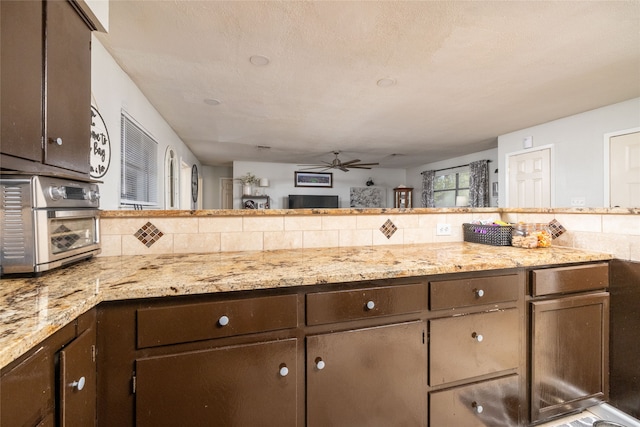 kitchen with backsplash, kitchen peninsula, dark brown cabinets, and ceiling fan