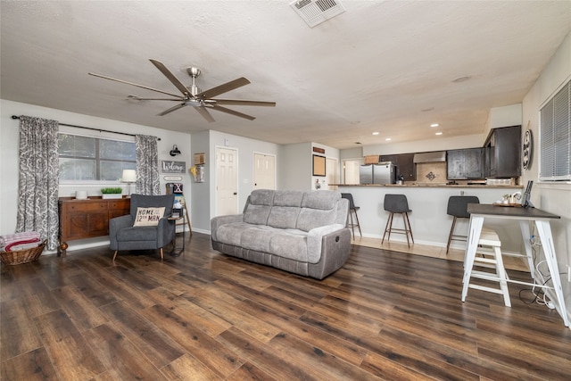 living room with dark wood-type flooring, ceiling fan, and a textured ceiling