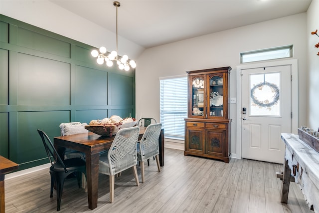 dining space featuring a notable chandelier, vaulted ceiling, and light hardwood / wood-style floors