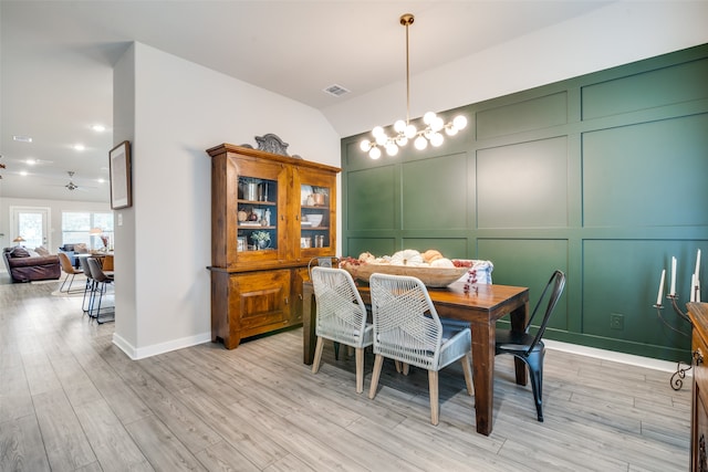 dining space with ceiling fan with notable chandelier, light wood-type flooring, and lofted ceiling