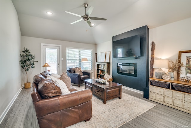 living room with a large fireplace, vaulted ceiling, ceiling fan, and wood-type flooring