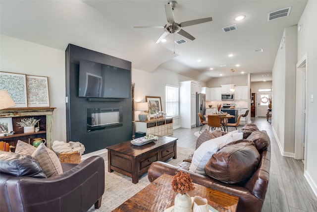 living room featuring ceiling fan, light hardwood / wood-style floors, and a large fireplace