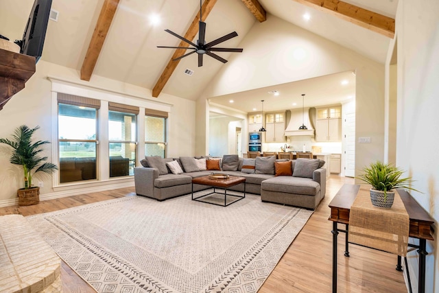 living room featuring beamed ceiling, ceiling fan, high vaulted ceiling, and light hardwood / wood-style flooring