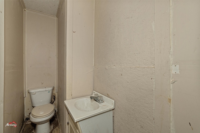 bathroom with a textured ceiling, vanity, and toilet