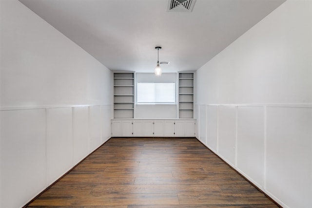 spare room with built in shelves and dark hardwood / wood-style floors