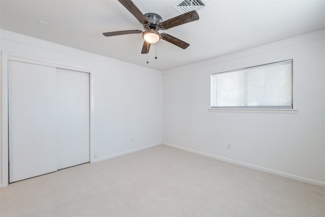 unfurnished bedroom with ceiling fan, light colored carpet, and a closet