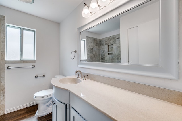 bathroom with vanity, hardwood / wood-style floors, toilet, and tiled shower