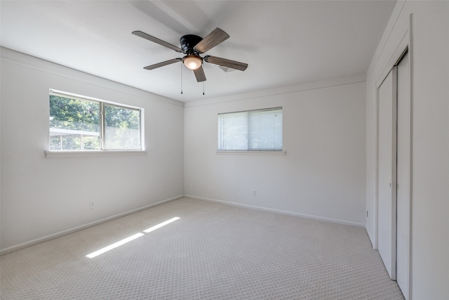 unfurnished bedroom with light carpet, a closet, and ceiling fan