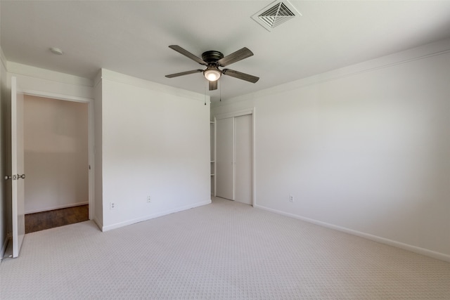 unfurnished bedroom featuring light carpet, a closet, and ceiling fan