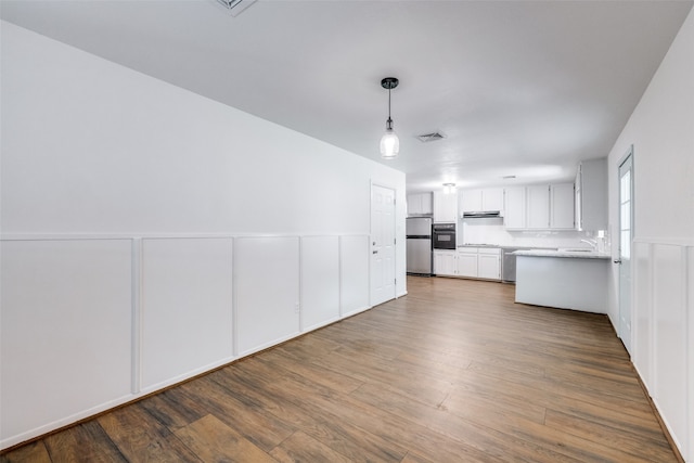 interior space with hanging light fixtures, stainless steel fridge, white cabinetry, and dark hardwood / wood-style floors