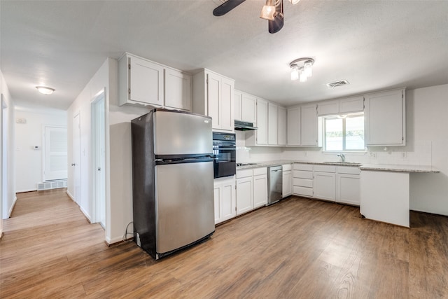 kitchen featuring ceiling fan, stainless steel refrigerator, oven, and white cabinetry