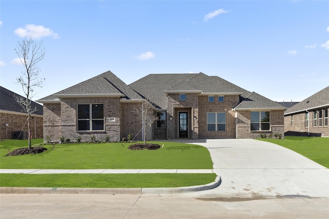 view of front of property with brick siding, a front yard, and roof with shingles