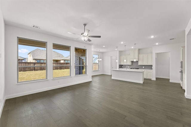 unfurnished living room featuring dark hardwood / wood-style flooring, ceiling fan, and sink