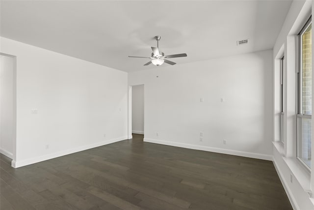 empty room featuring visible vents, baseboards, dark wood-type flooring, and ceiling fan