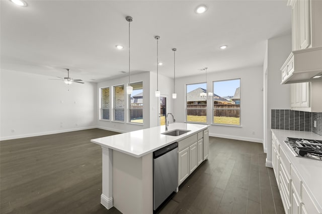 kitchen with appliances with stainless steel finishes, ceiling fan, sink, white cabinetry, and an island with sink