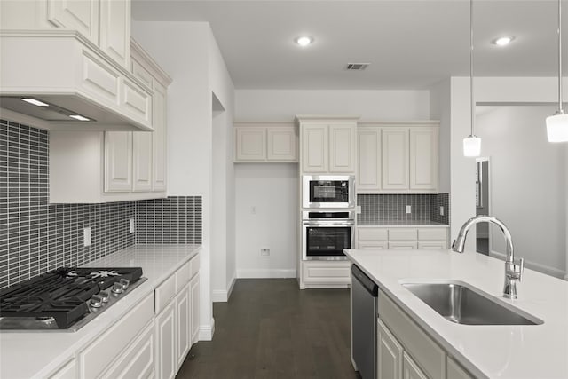 kitchen featuring visible vents, a sink, stainless steel appliances, light countertops, and dark wood-style flooring