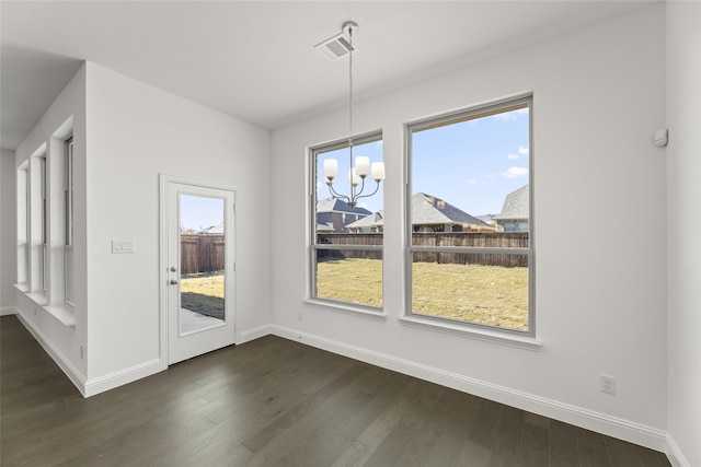 unfurnished dining area with a wealth of natural light, a notable chandelier, and dark wood finished floors