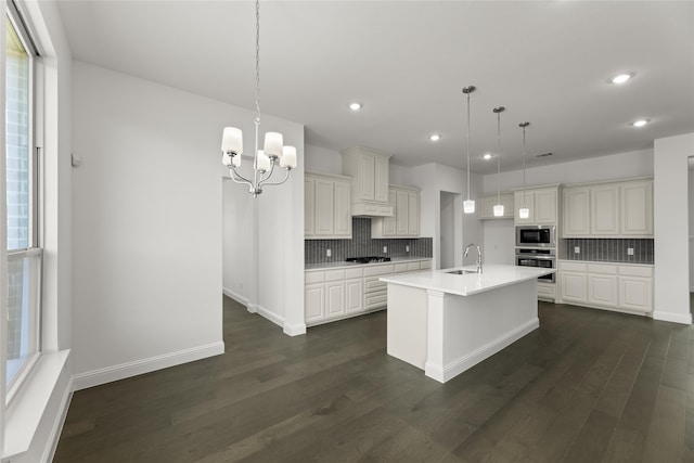 kitchen with a sink, backsplash, stainless steel appliances, light countertops, and dark wood-style flooring