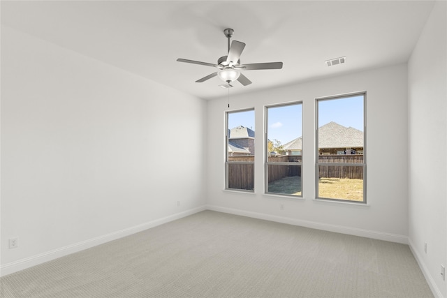 unfurnished room featuring light carpet, visible vents, ceiling fan, and baseboards