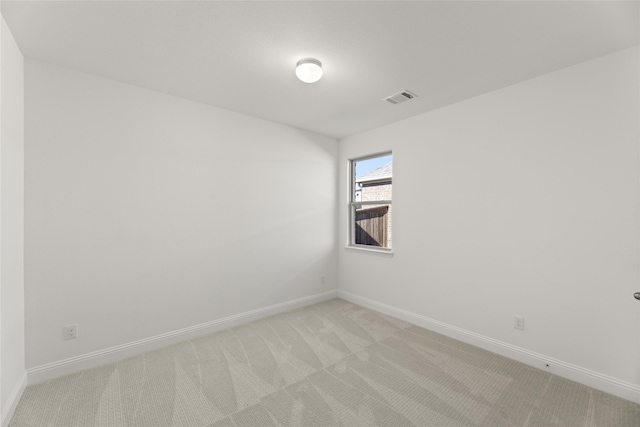 empty room featuring visible vents, light colored carpet, and baseboards