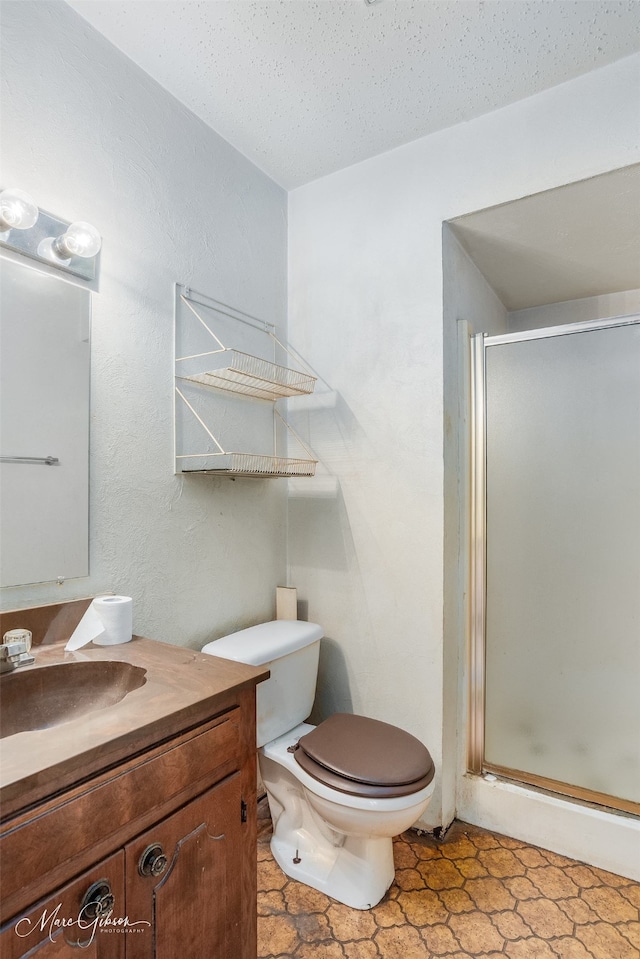 bathroom with walk in shower, vanity, toilet, and a textured ceiling