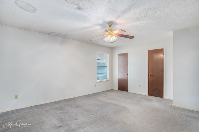 carpeted empty room with ceiling fan and a textured ceiling