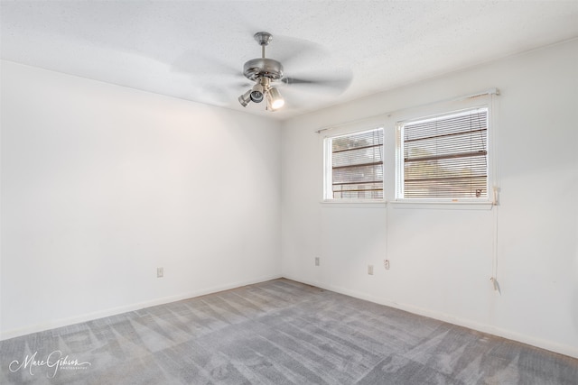 spare room featuring ceiling fan, light colored carpet, and a textured ceiling